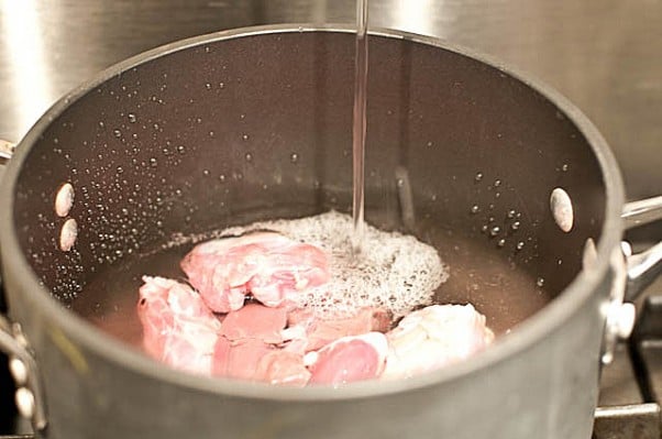 Image of medium saucepan filled with turkey giblets for gravy recipe and water being added. // addapinch.com