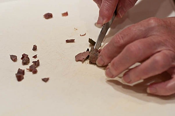 Giblets being chopped on a white cutting board with a woman's hands. // addapinch.com
