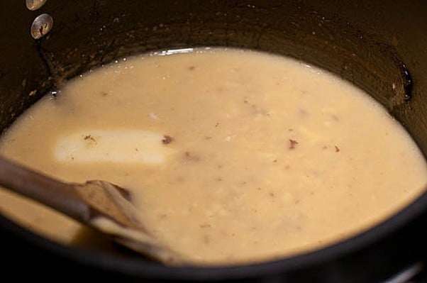 Image of base for giblet gravy in a saucepan with a wooden spoon. // addapinch.com