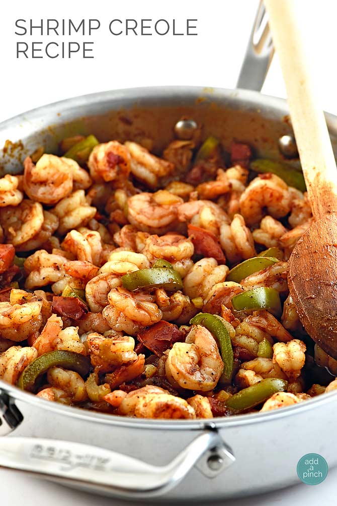 Shrimp Creole with shrimp, green pepper slices and tomatoes with a wooden spoon in a stainless steel skillet 