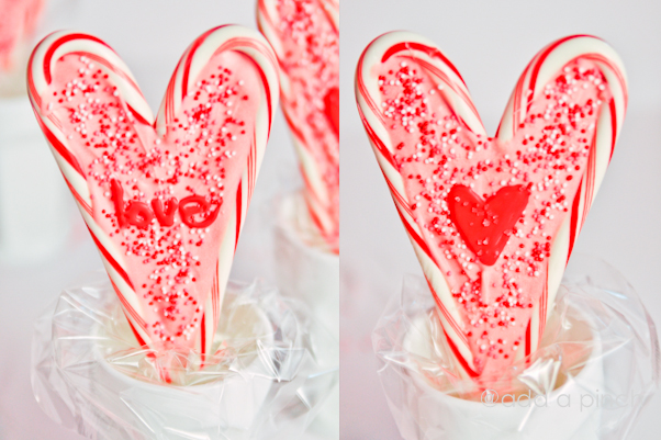 Heart shaped lollipops in a white glass on a white surface.