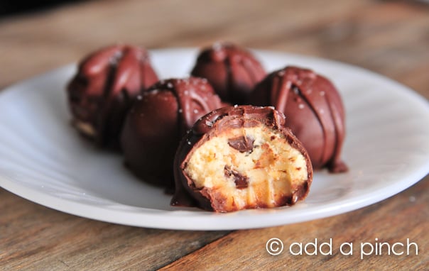 Cookie dough truffles on a white plate on wooden surface.