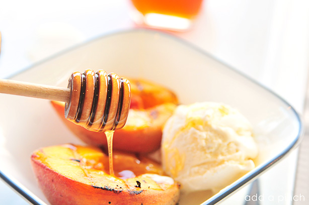 Bowl of Grilled Peaches vanilla ice cream being drizzled with honey