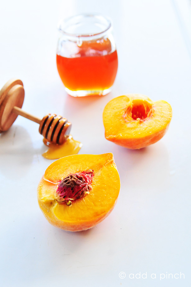 Fresh peach cut in half with jar of honey