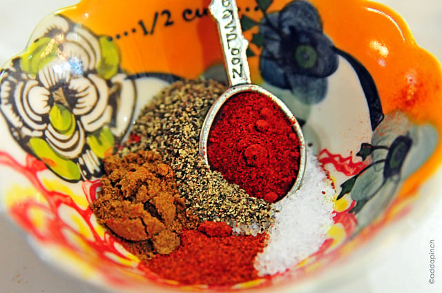 Colorful measuring bowl with dry spices and pewter measuring spoon // addapinch.com