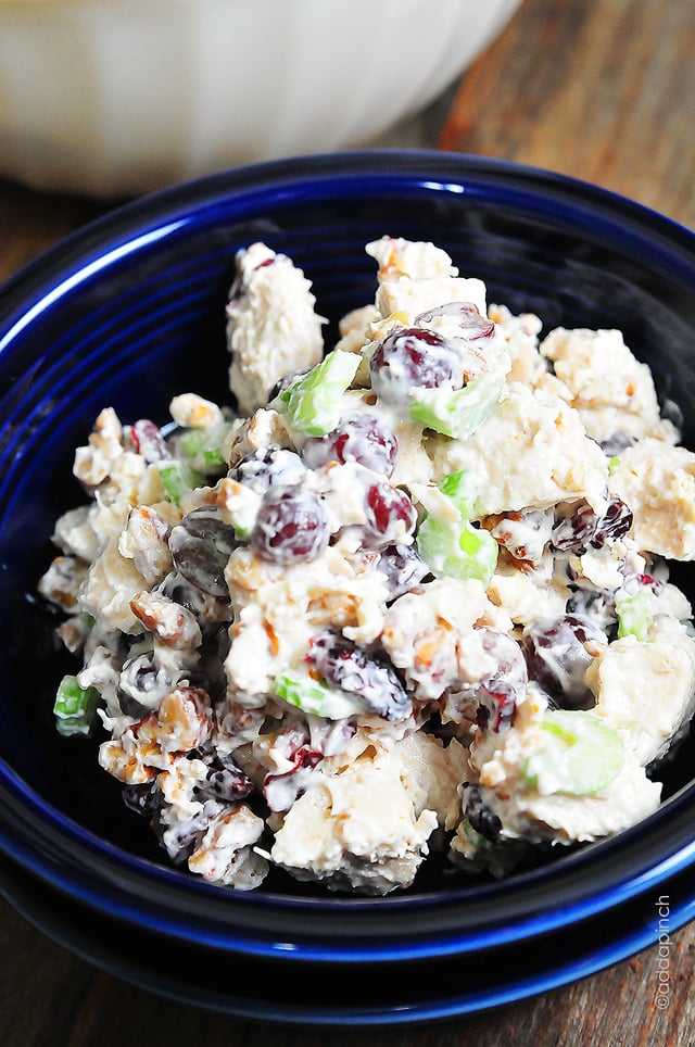 Closeup photograph of chicken salad made with grapes, raisins, celery and pecans in a blue bowl. // addapinch.com