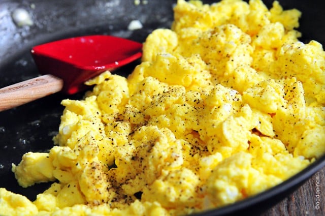 Closeup of scrambled eggs in skillet with rubber spatula - addapinch.com