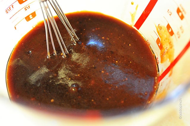 Marinade in a glass measuring cup with a metal whisk.