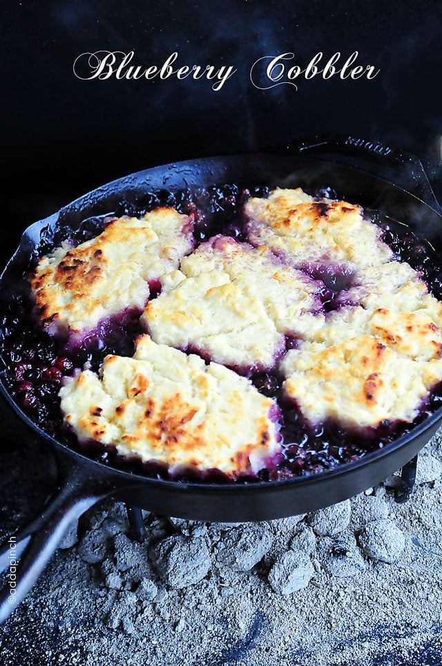 Cast iron skillet with bubbly Blueberry Cobbler cooked over a campfire. 