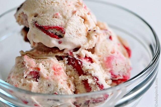 Loads of fresh strawberries in scoops of strawberry ice cream served in glass bowl // addapinch.com