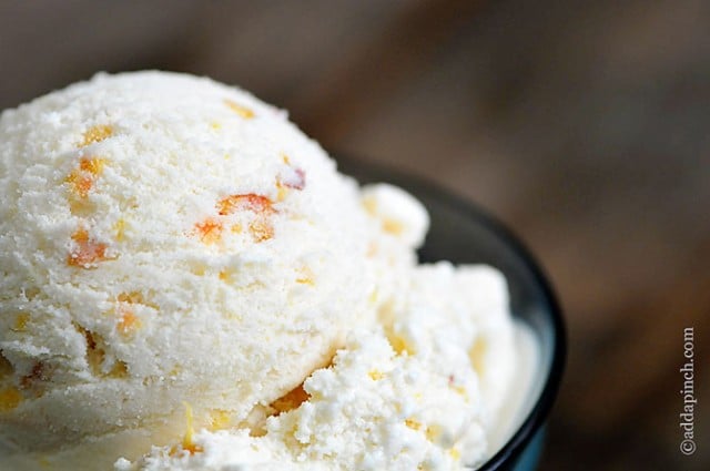 Scoop of peach ice cream in glass ice cream dish - ©addapinch.com