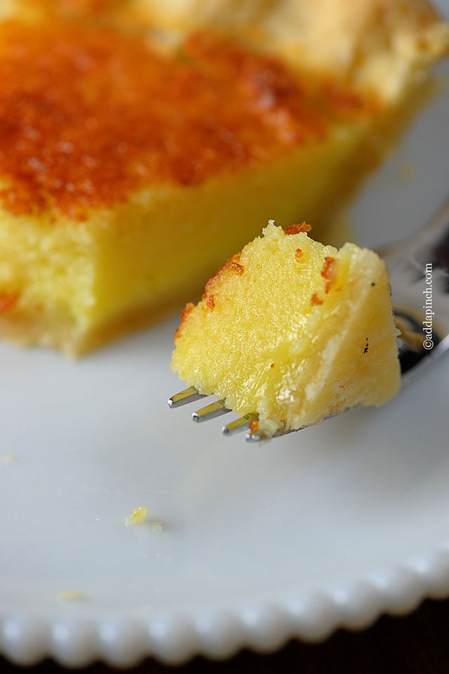 Buttermilk pie on a white plate with a bite on fork. 