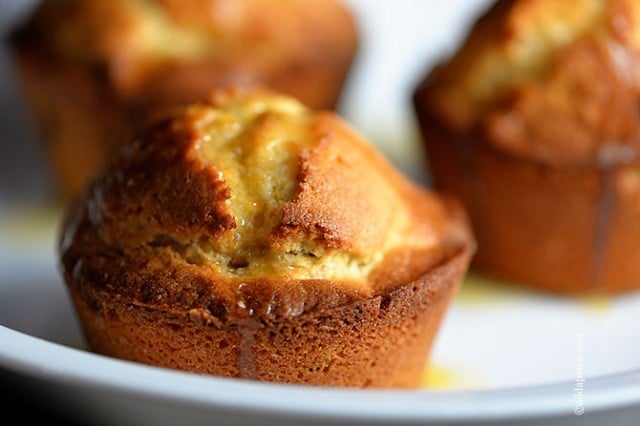 Cranberry Orange Muffins on white plate with bit of glaze drizzled down sides.