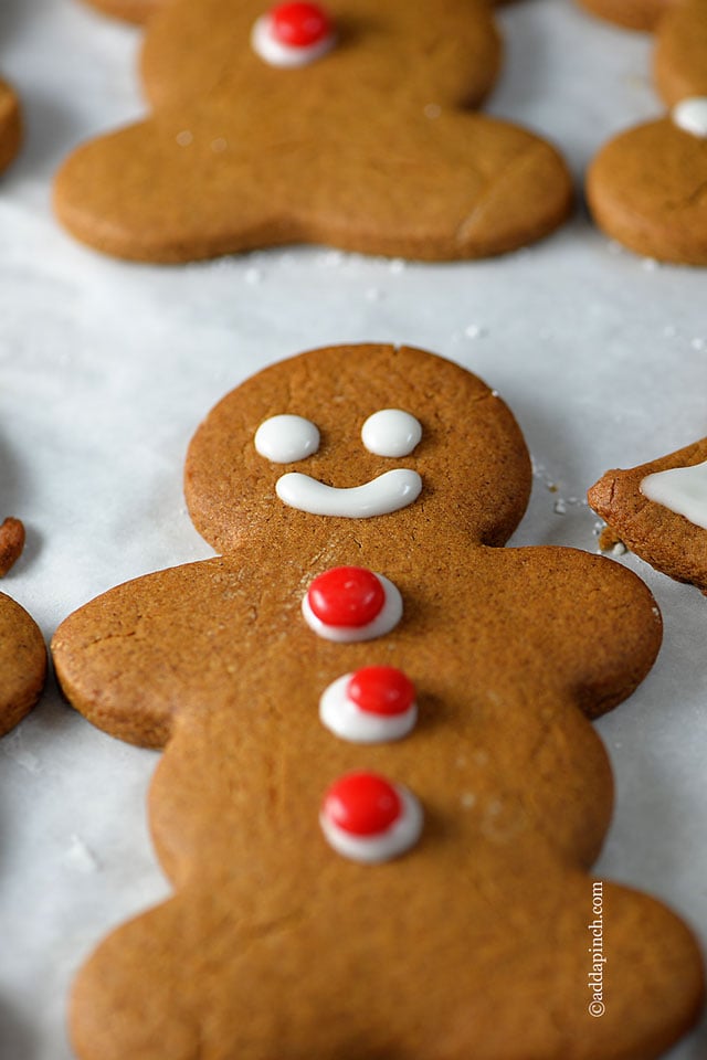 Photo of gingerbread cookies decorated with red candy buttons on white background.