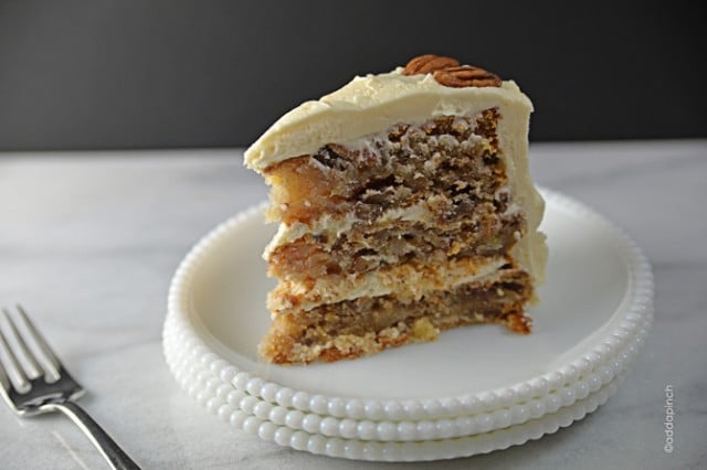 White hobnail plates are stacked on a marble counter. A slice of hummingbird cake sits on the top plate. 