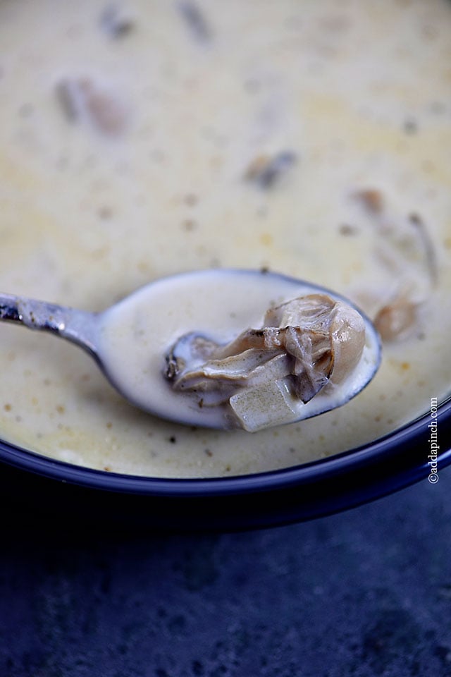 Oyster Stew Recipe with oysters ladled into a spoon from a blue bowl