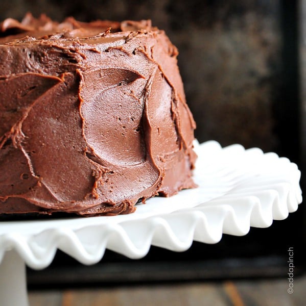 Fluted edge white heirloom cake stand holds chocolate cake with Chocolate Buttercream Frosting - ©addapinch.com