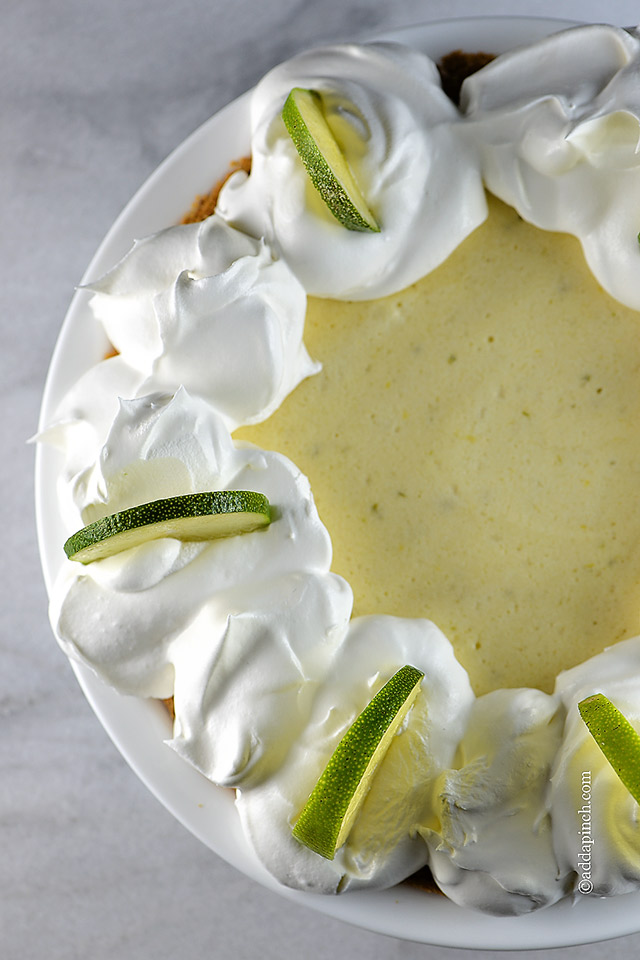 Closeup of pie with limes and whipped cream on marble countertop. 