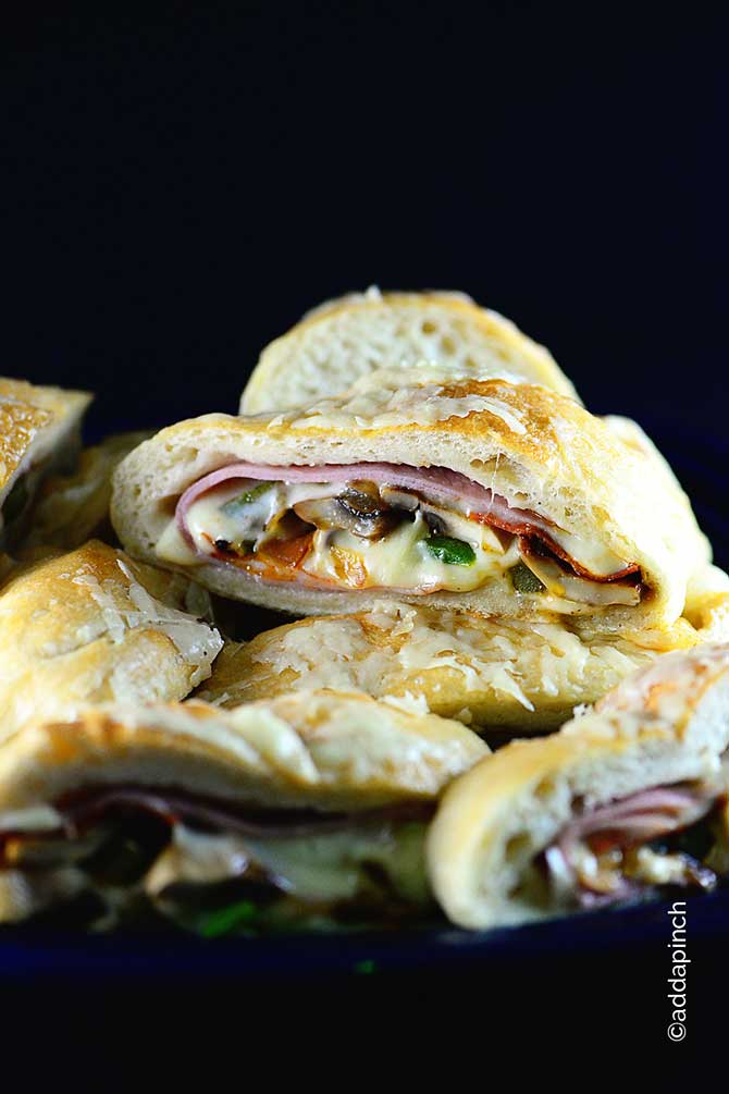 Stacks of sliced Stromboli filled with meats, cheese, veggies and topped with melted butter and shaved Parmesan and baked til golden - from addapinch.com