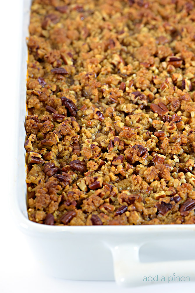 White casserole dish with handles holds Sweet Potato Casserole covered in nutty pecan streusel topping