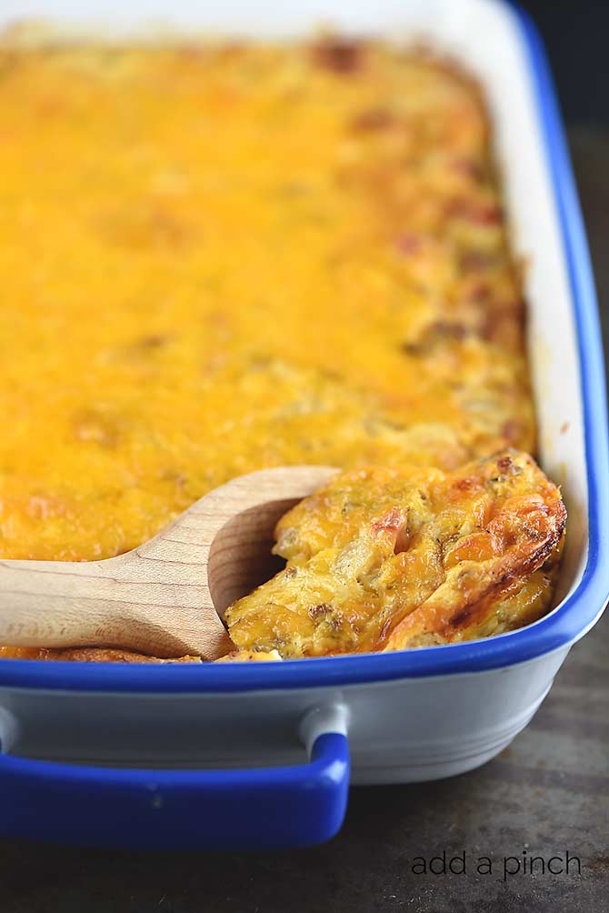 Baking dish filled with golden cheesy Breakfast Casserole being scooped with a wooden spoon