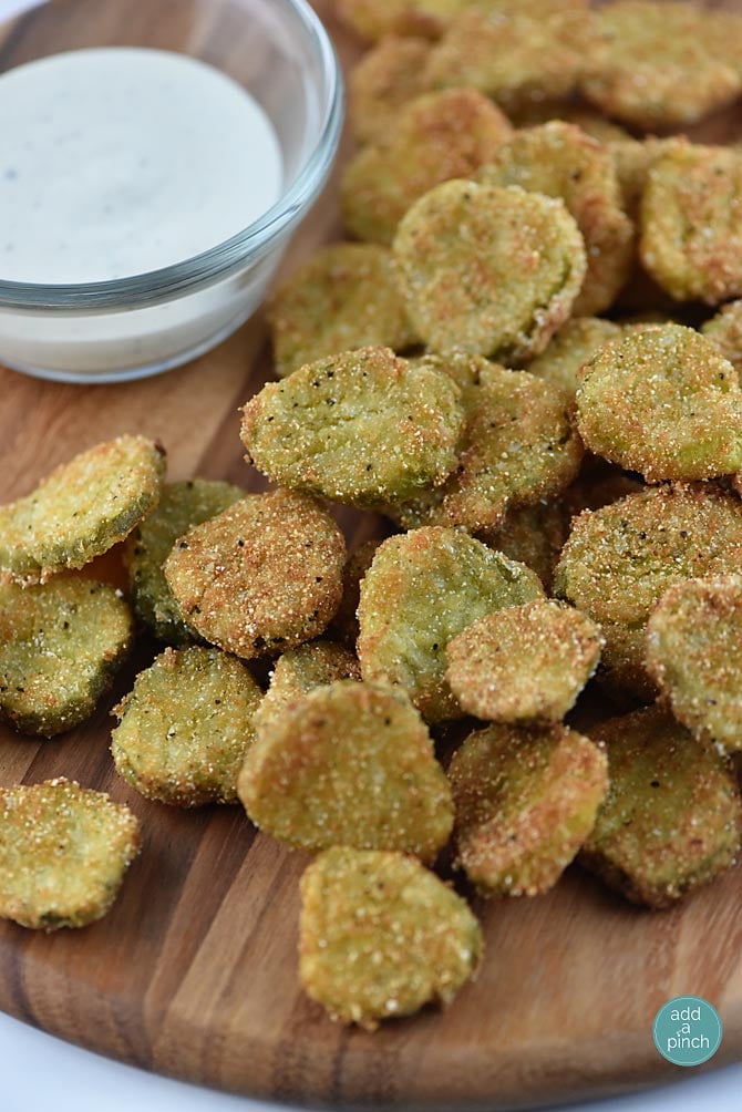 Fried Dill Pickles on a wooden serving board - addapinch.com