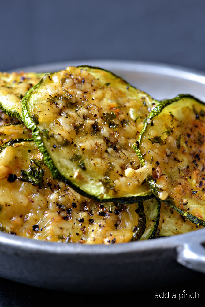 Closeup of Zucchini Chips withmelted parmesan in a pewter serving dish // addapinch.com