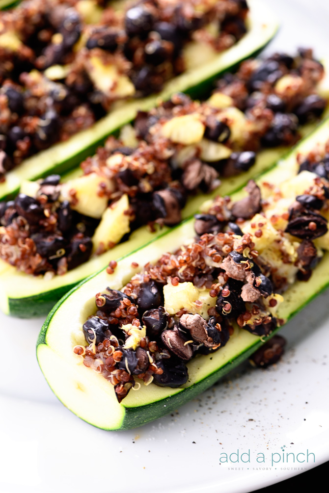 Black beans, quinoa and cheese stuffed into zucchini boats on a baking dish.