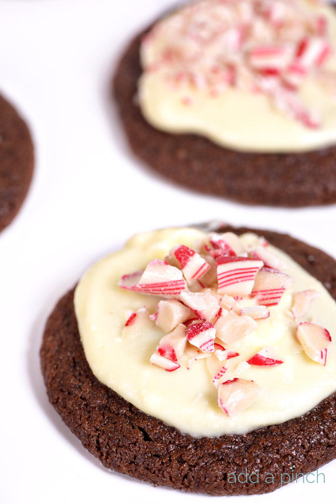 A white tray holds peppermint bark sugar cookies - chocolate sugar cookies topped with white chocolate and crushed candy canes.