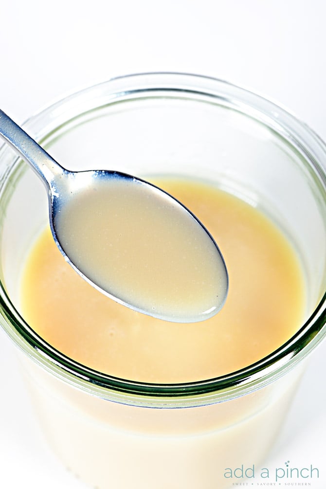 Homemade Sweetened Condensed Milk in a glass jar with a teaspoon