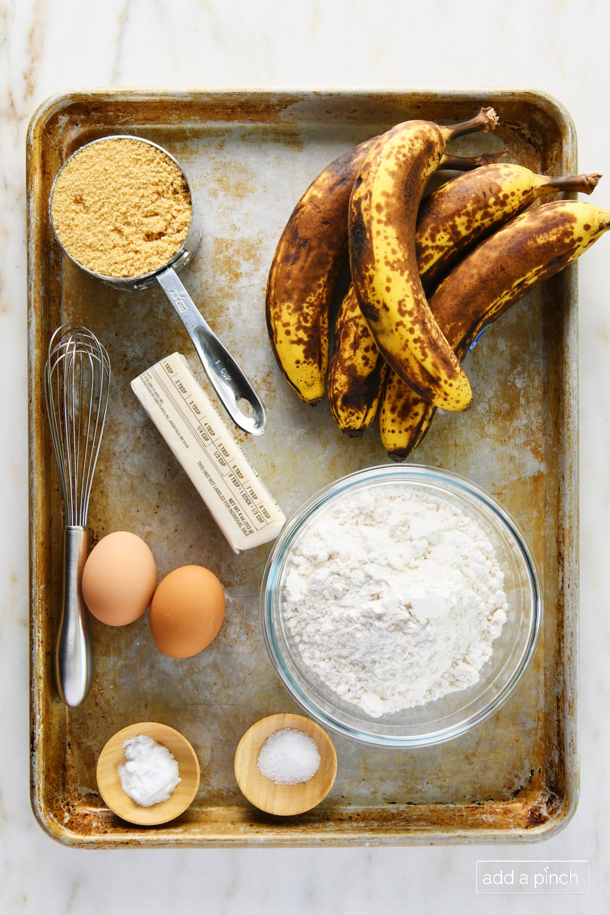 Ingredients used to make best banana muffins on a baking sheet on a marble surface