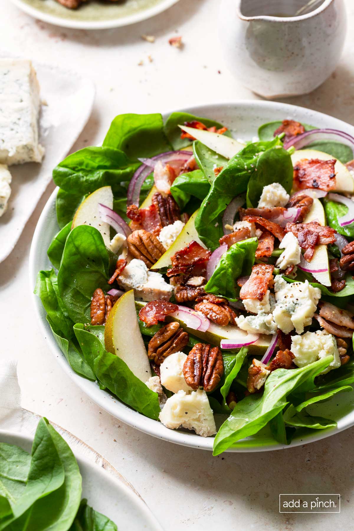 Photo of the best spinach salad with pears, bacon, onion, blue cheese, and hot bacon dressing.
