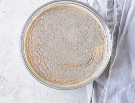 Photo of yeast sprinkled on water in a glass bowl.