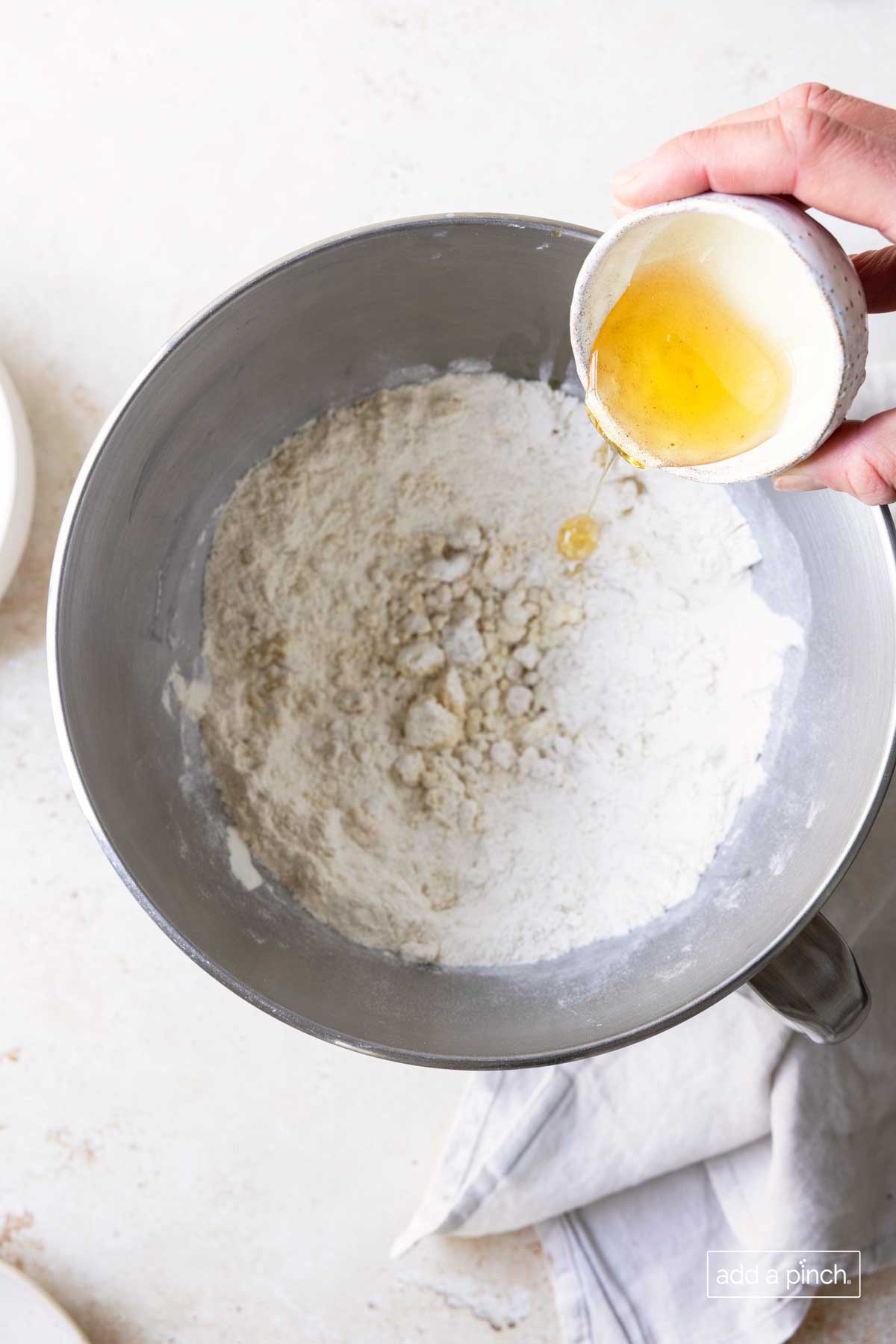 Honey being poured into a bowl with flour mixture to make pizza dough.