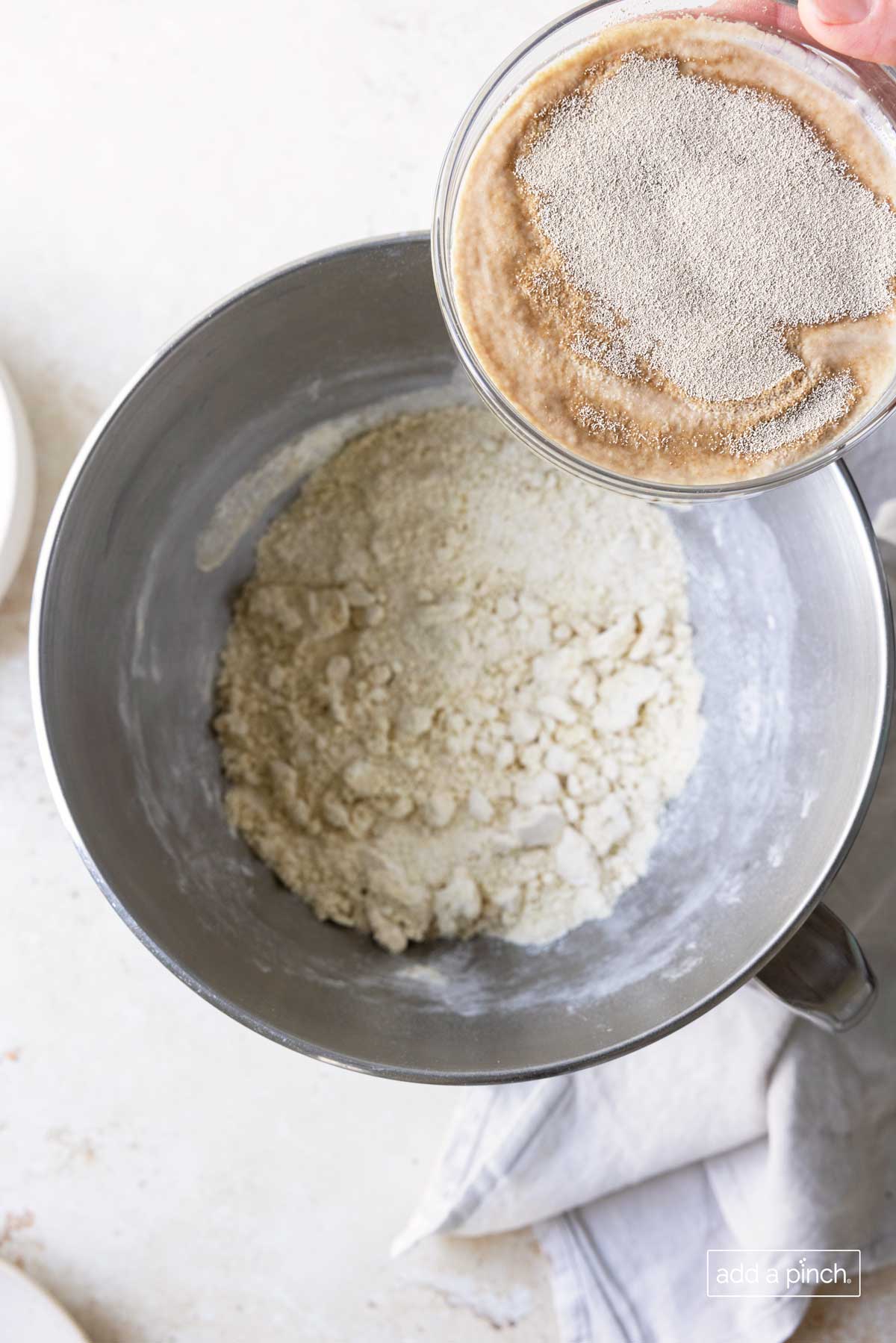 Yeast is combined with the flour mixture in the bowl to make pizza dough.