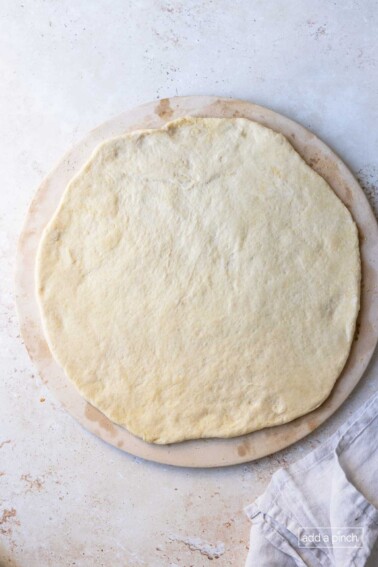 Pizza dough on a pizza stone ready for toppings.