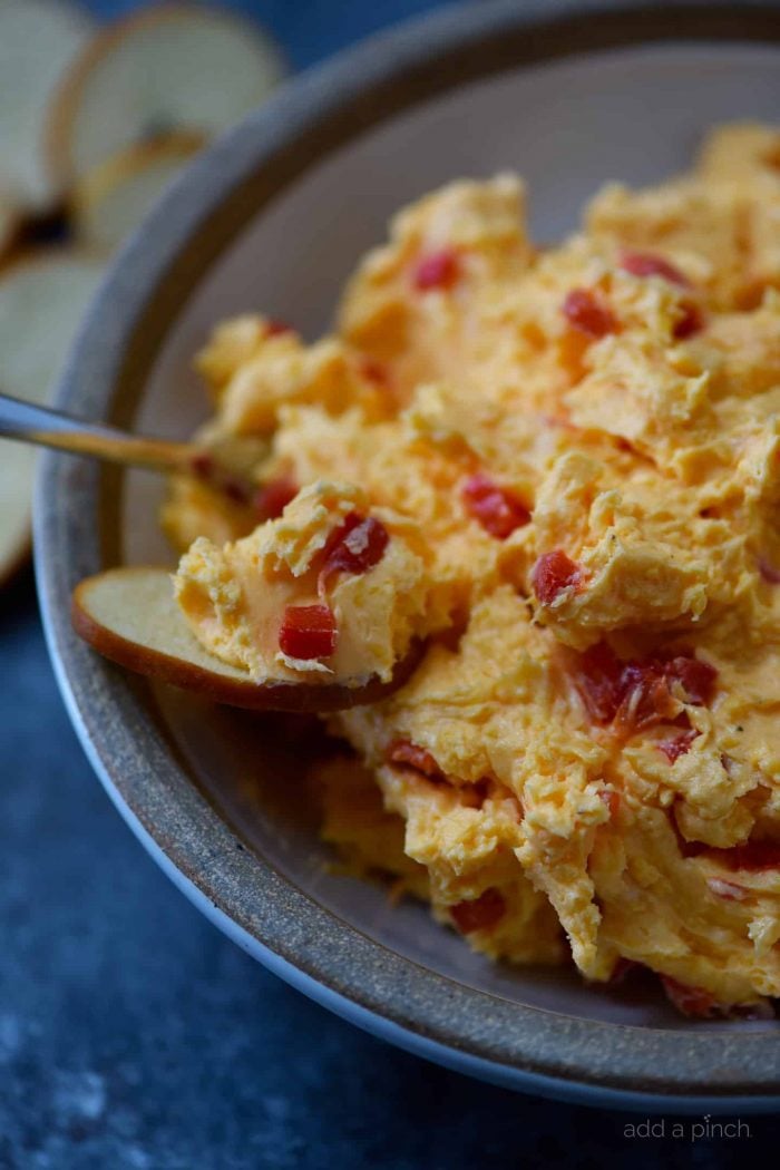 Closeup of pimento cheese being scooped onto a bagel chip. 