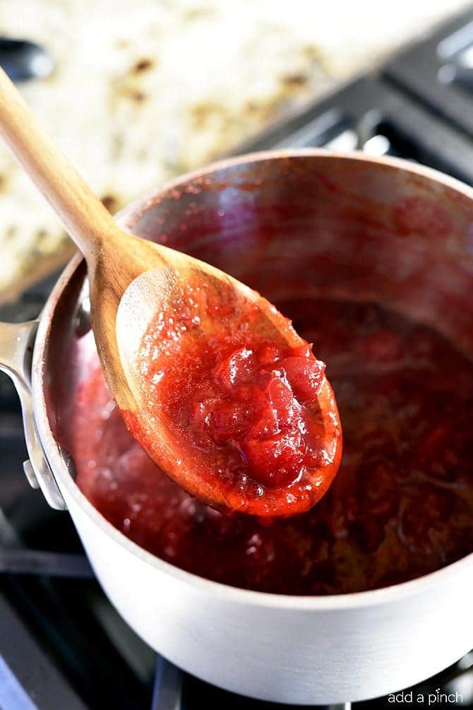 Classic Cranberry Sauce - Testing consistency and thickness of cooked Cranberry Sauce with a wooden spoon. // addapinch.com