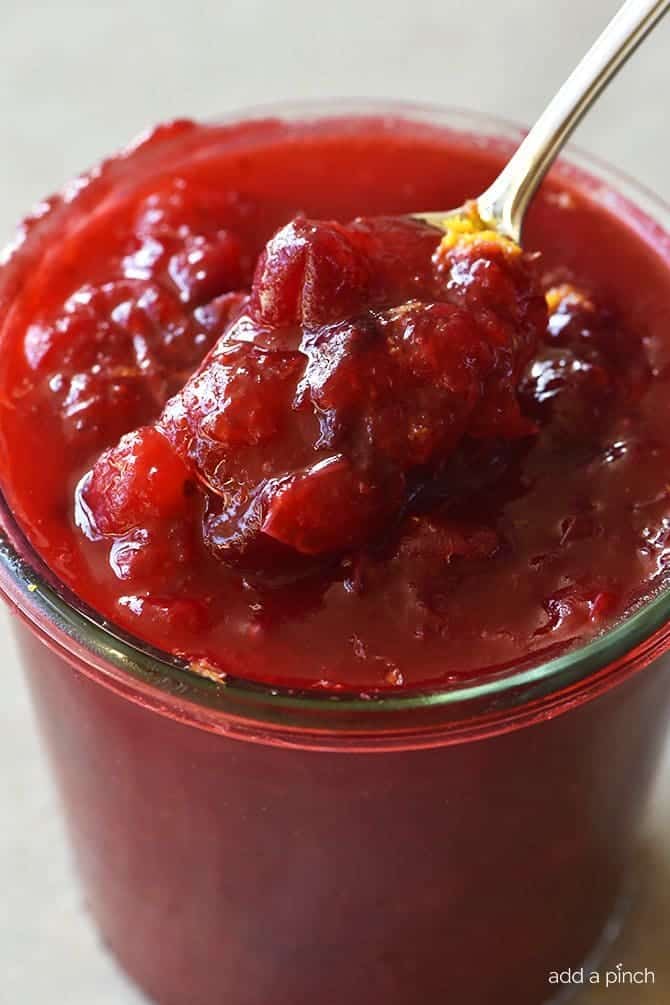 Klassische Cranberry-Sauce im Glas mit Löffel Zugabe von frischer Orangenschale // addapinch.com