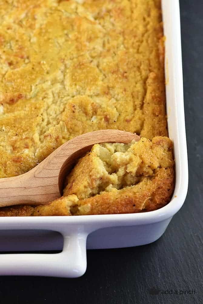 Southern cornbread dressing with a wooden spoon in a white baking dish.