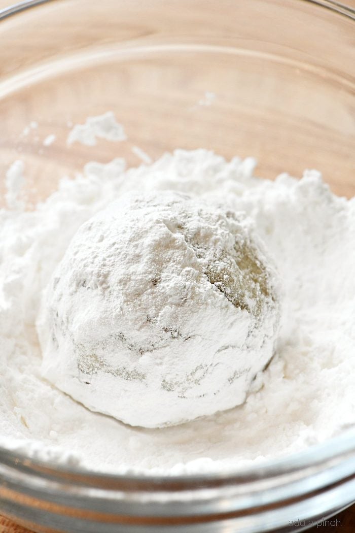 Snowball Cookie being rolled in bowl of powdered sugar 