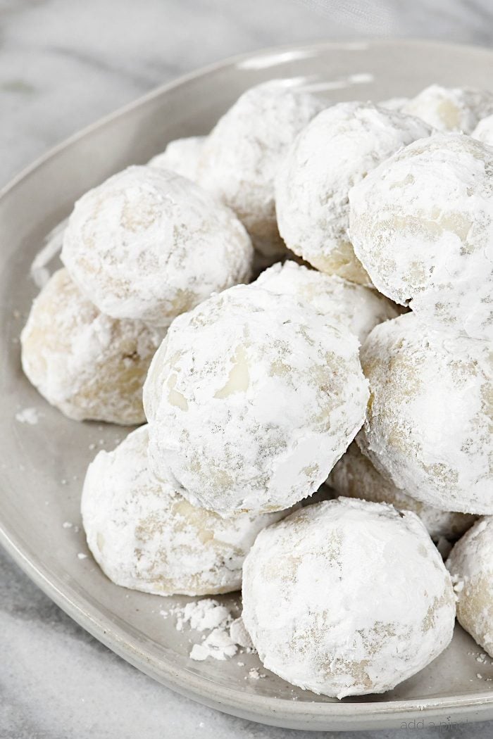 Pecan Sandies  or Snowball Cookies, also called Mexican Wedding Cookies, covered in powdered sugar, stacked on plate 