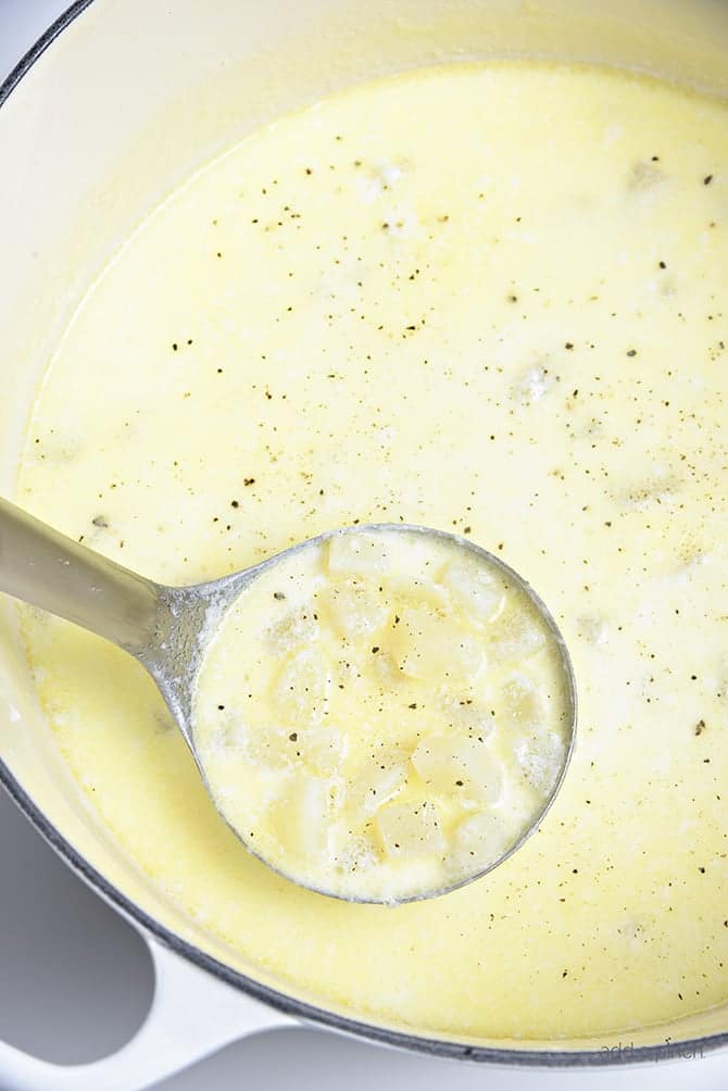 Potato Soup cooking in enamel Dutch oven and scooped into a laddle - addapinch.com