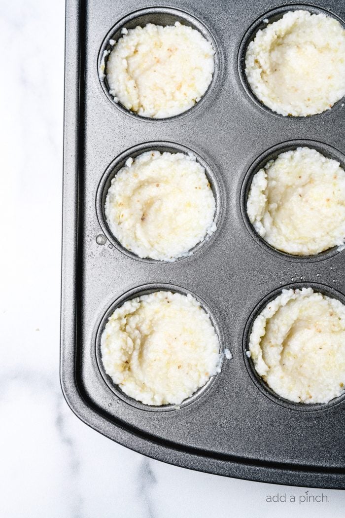 Grits pressed into a muffin tin to bake - addapinch.com