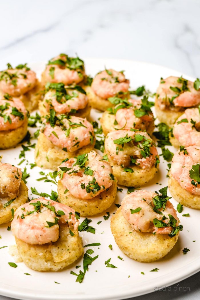 Several parsley-topped shrimp and grits bites served on a white plate  // addapinch.com
