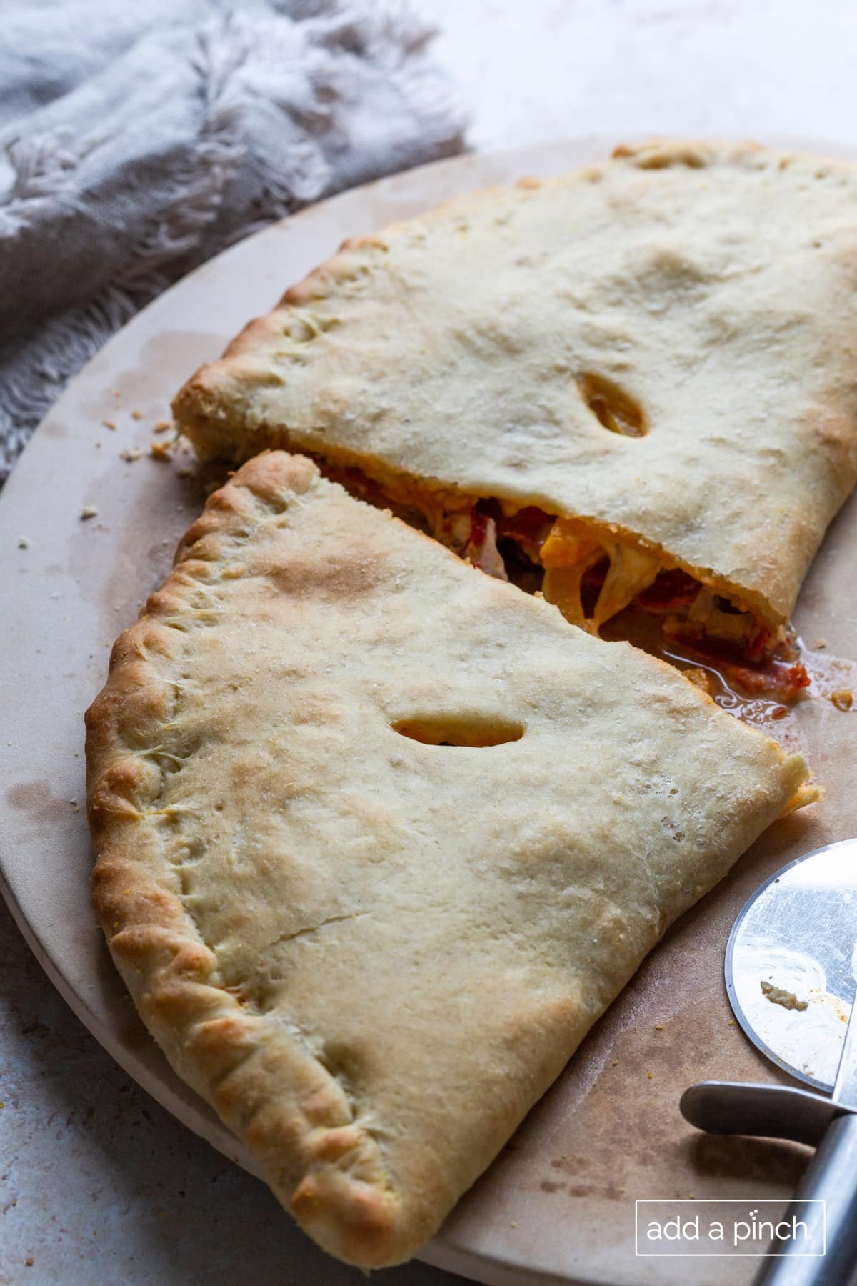 Photo of freshly baked Calzone on a pizza stone sliced in half ready to serve. 