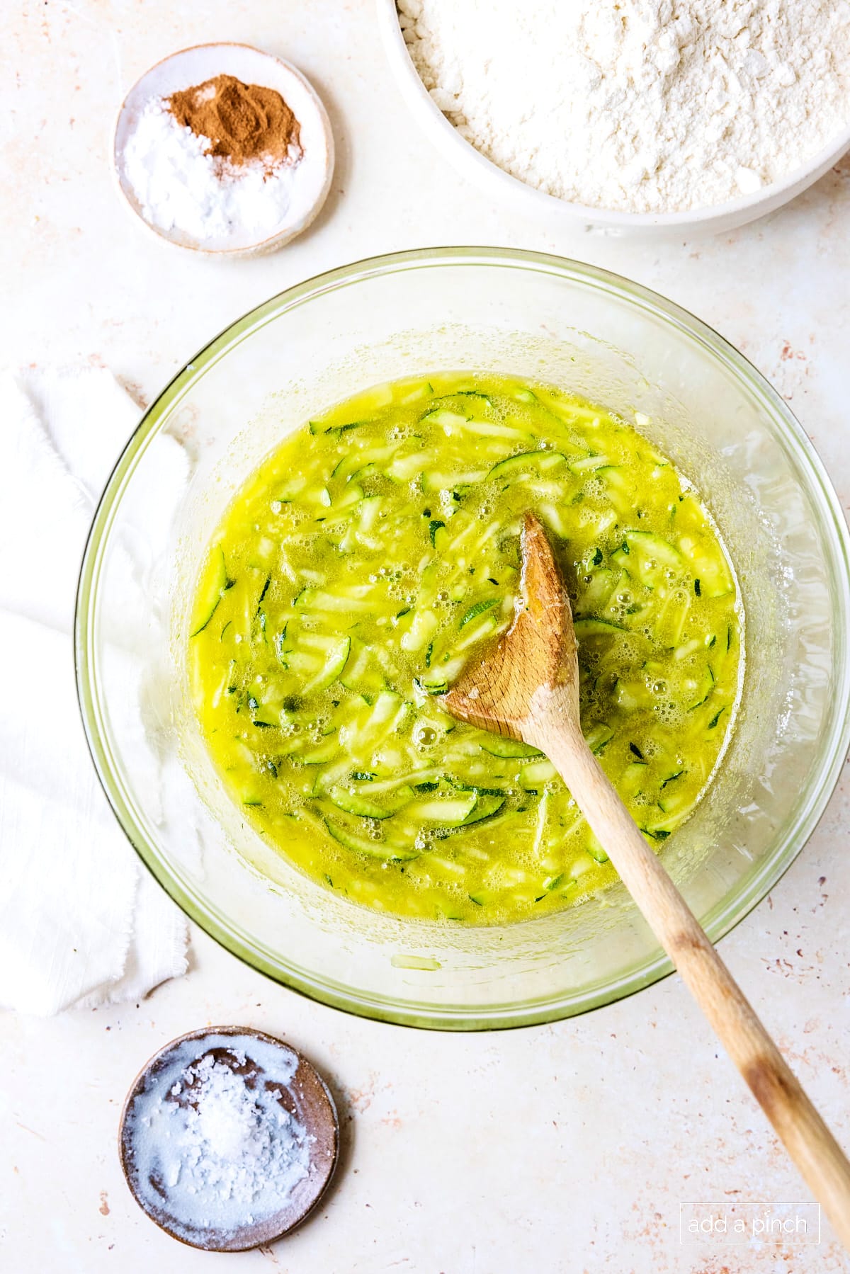 Mix sugar, zucchini and egg mixture in a glass bowl with a wooden spoon.