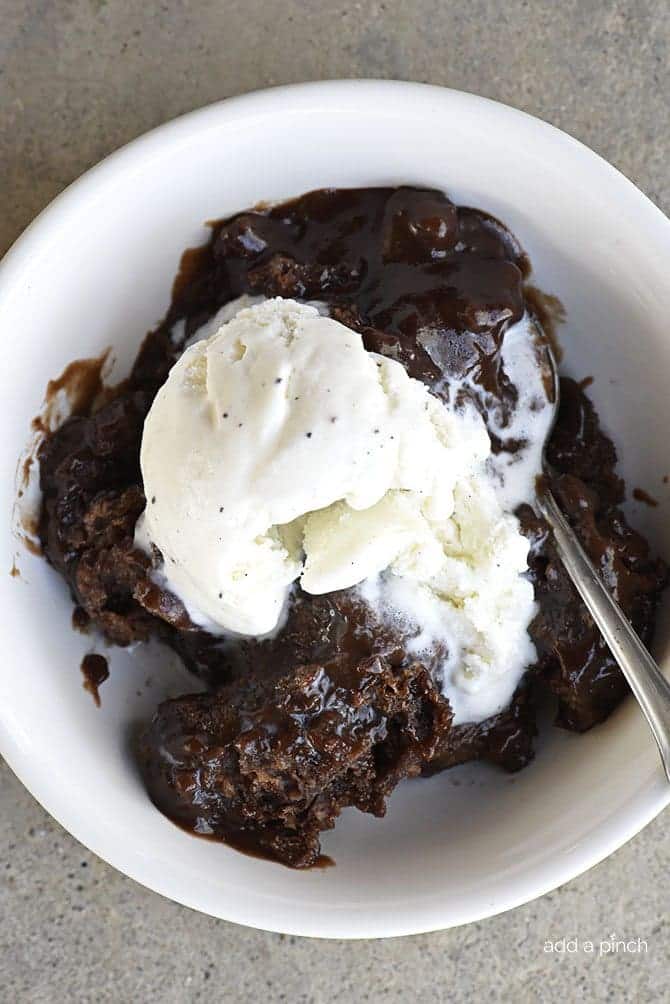Bowl of chocolate cobbler and a spoon topped with vanilla ice cream. // addapinch.com