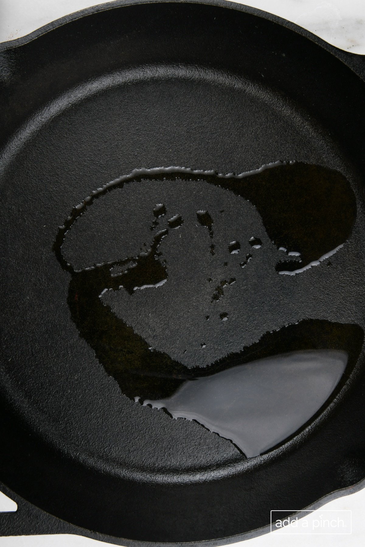 Olive oil added to a cast iron skillet.