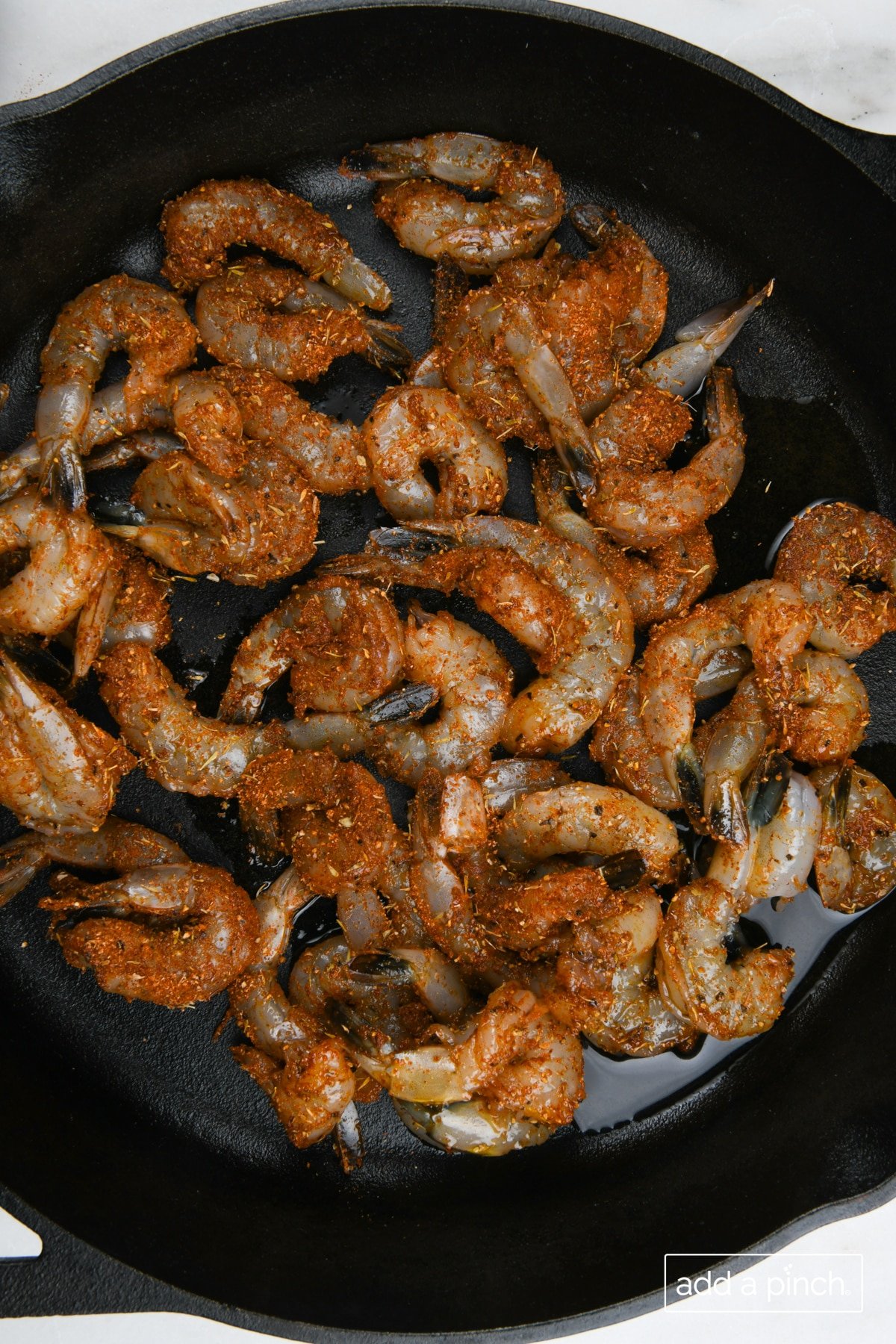 Seasoned shrimp in a cast iron skillet.